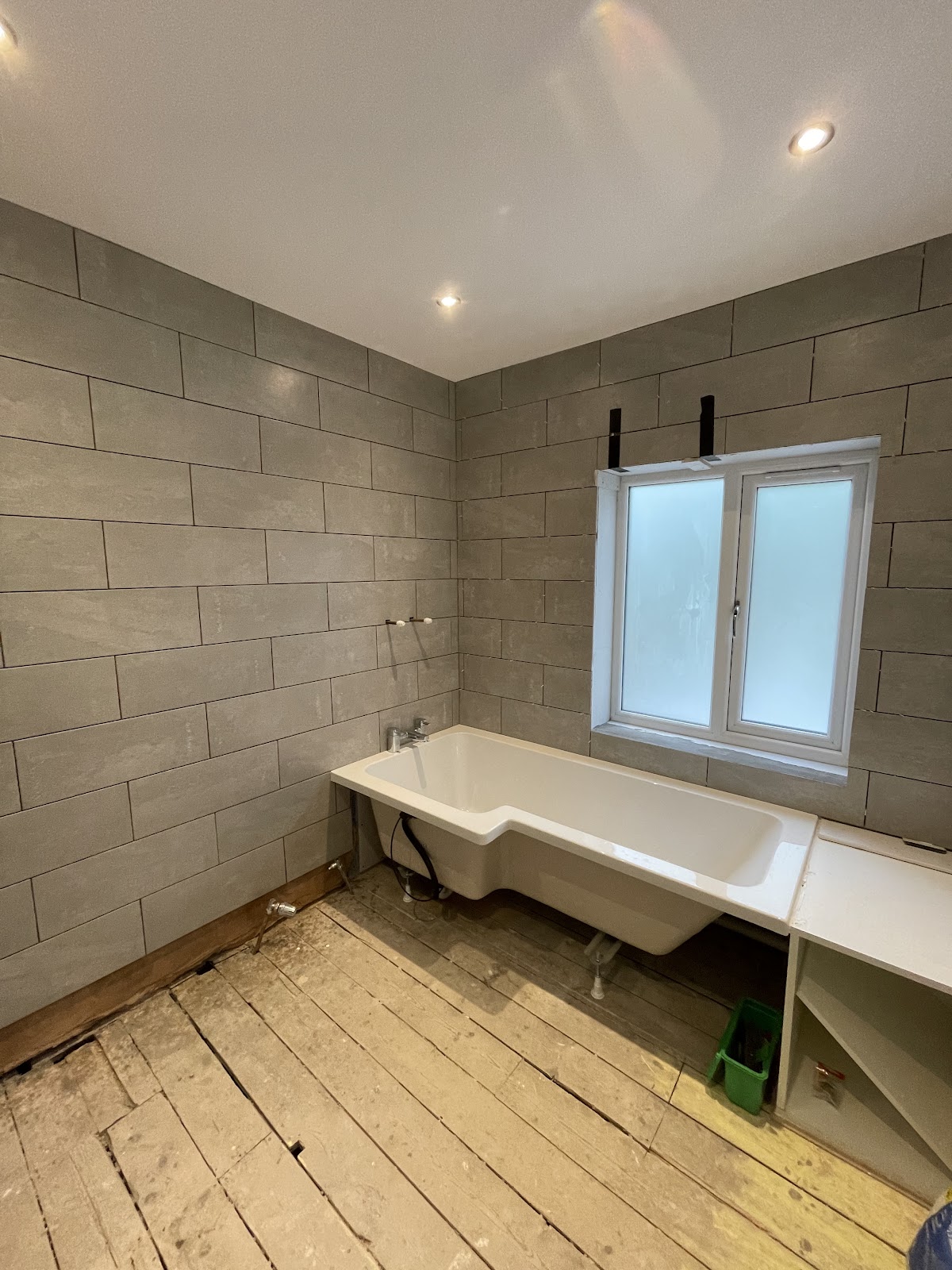 Newly tiled bathroom with modern grey tiling and recessed lighting